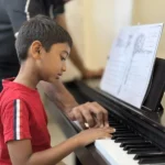 A boy at the piano with his teacher