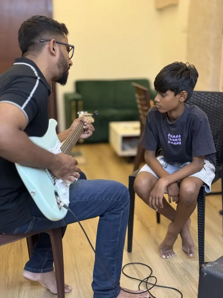 Sabi Thankachan demonstrating electric guitar to a boy