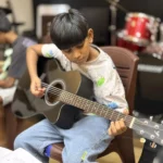 A young boy learning acoustic guitar
