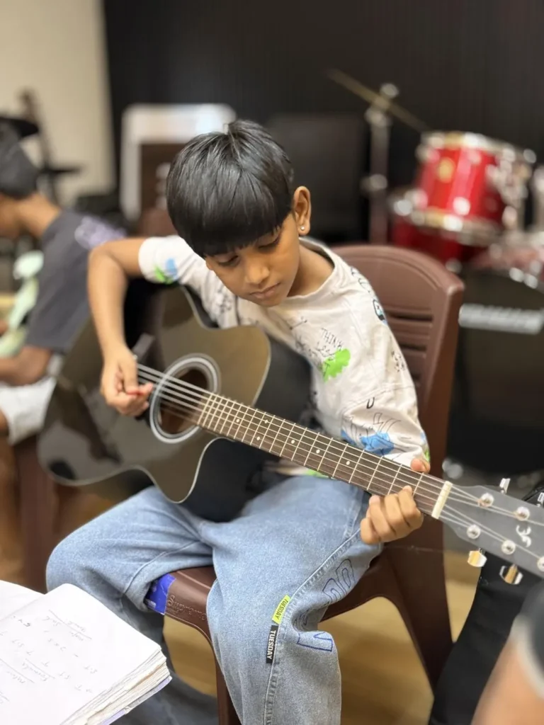 A young boy learning acoustic guitar